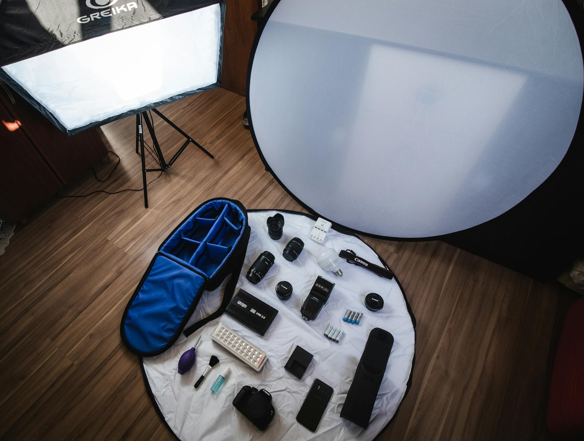 Top view of a professional photography studio setup with essential equipment displayed on a wooden floor.